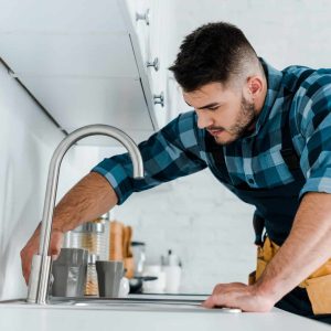 selective-focus-of-handsome-handyman-working-near-sink-in-kitchen.jpg